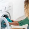 Nurse handling freshly washed medical scrubs in a laundry room with a dryer and detergent in the background.